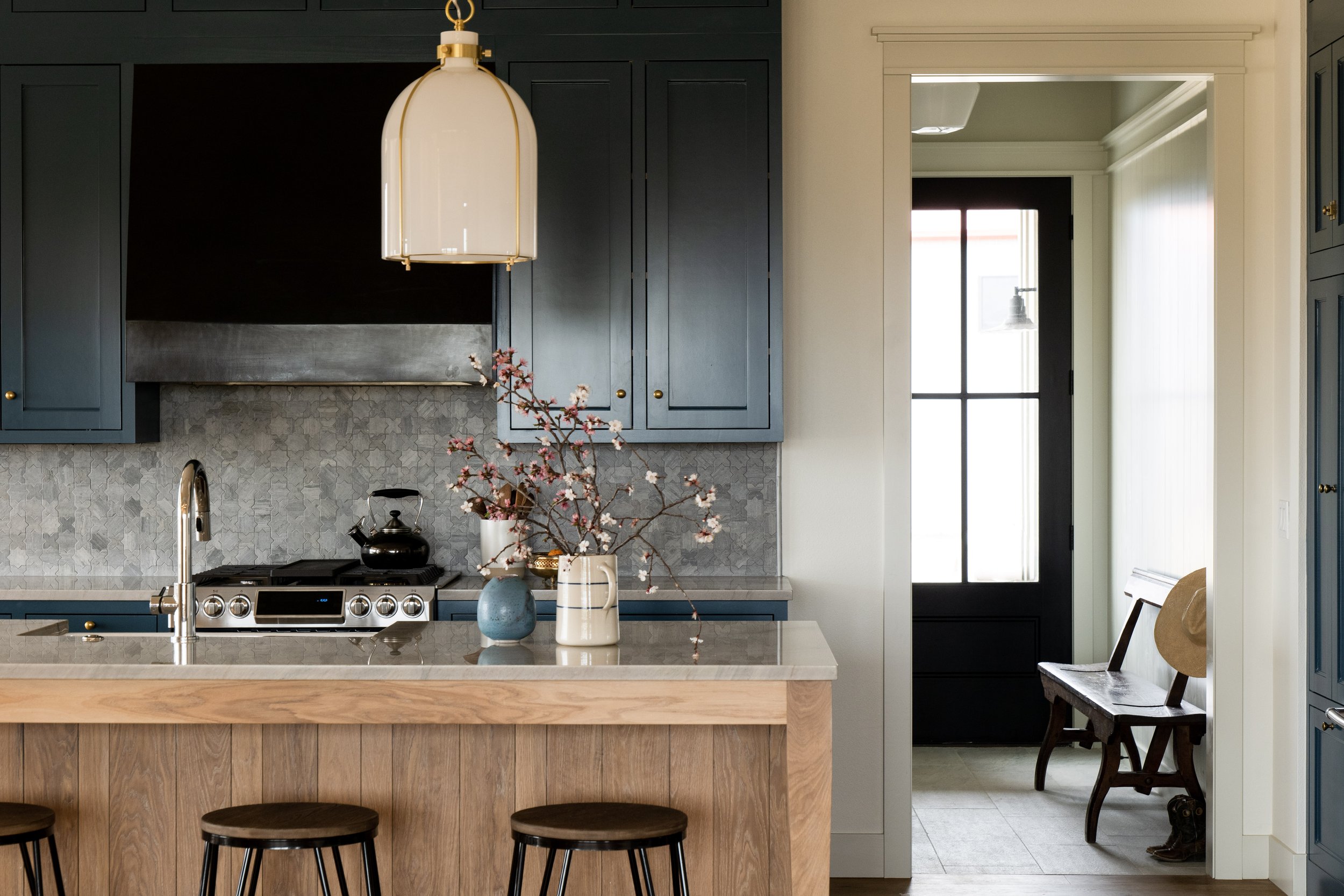 A bright, cheery kitchen in a newly designed and constructed home.  Blue cabinets, geometric marble backsplash, quartzite countertops and a white oak island are designed to invoke a sense of peace and tranquility.